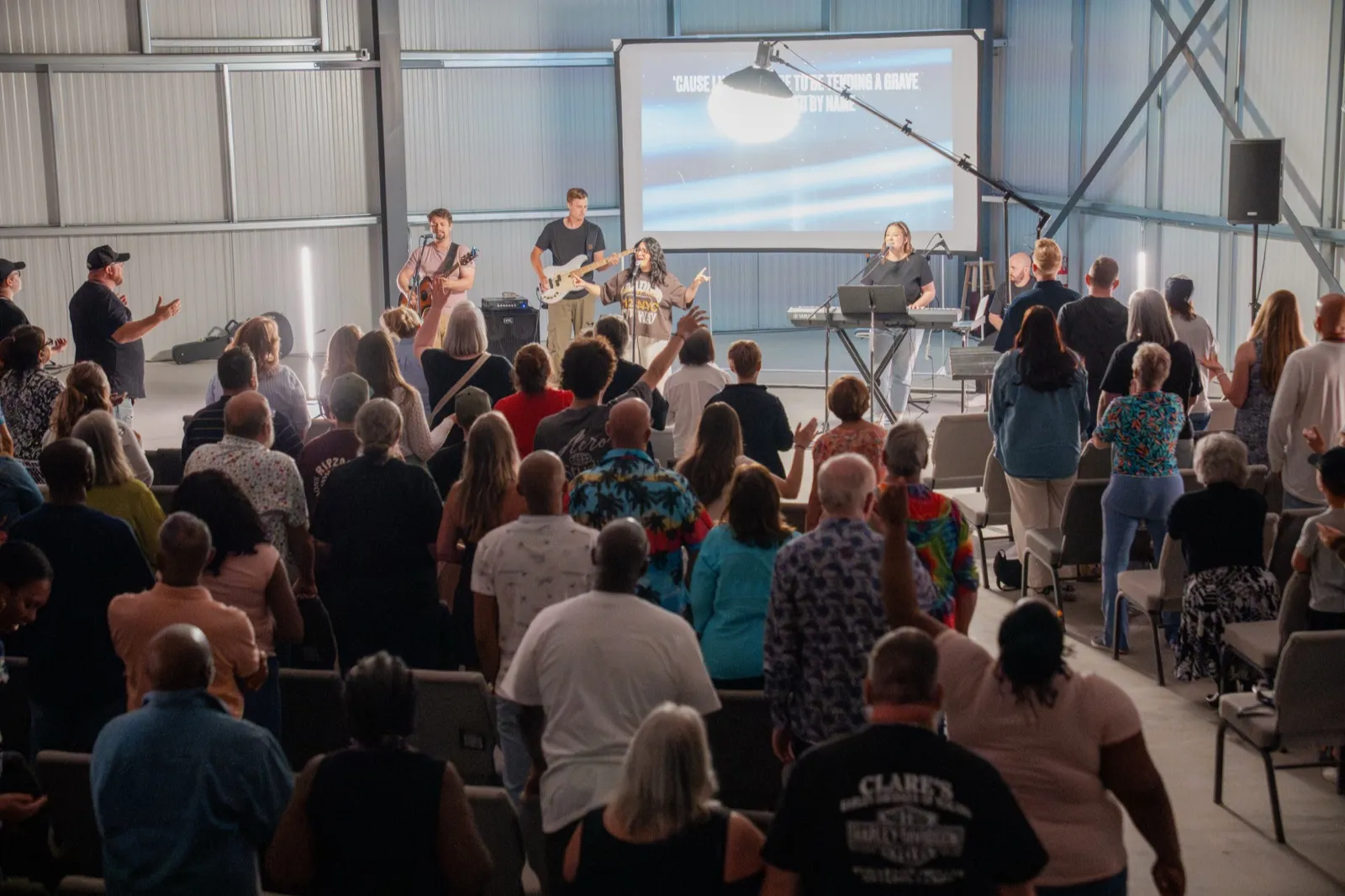The band leading extended worship at Encounter Night while the room stands with hands raised.