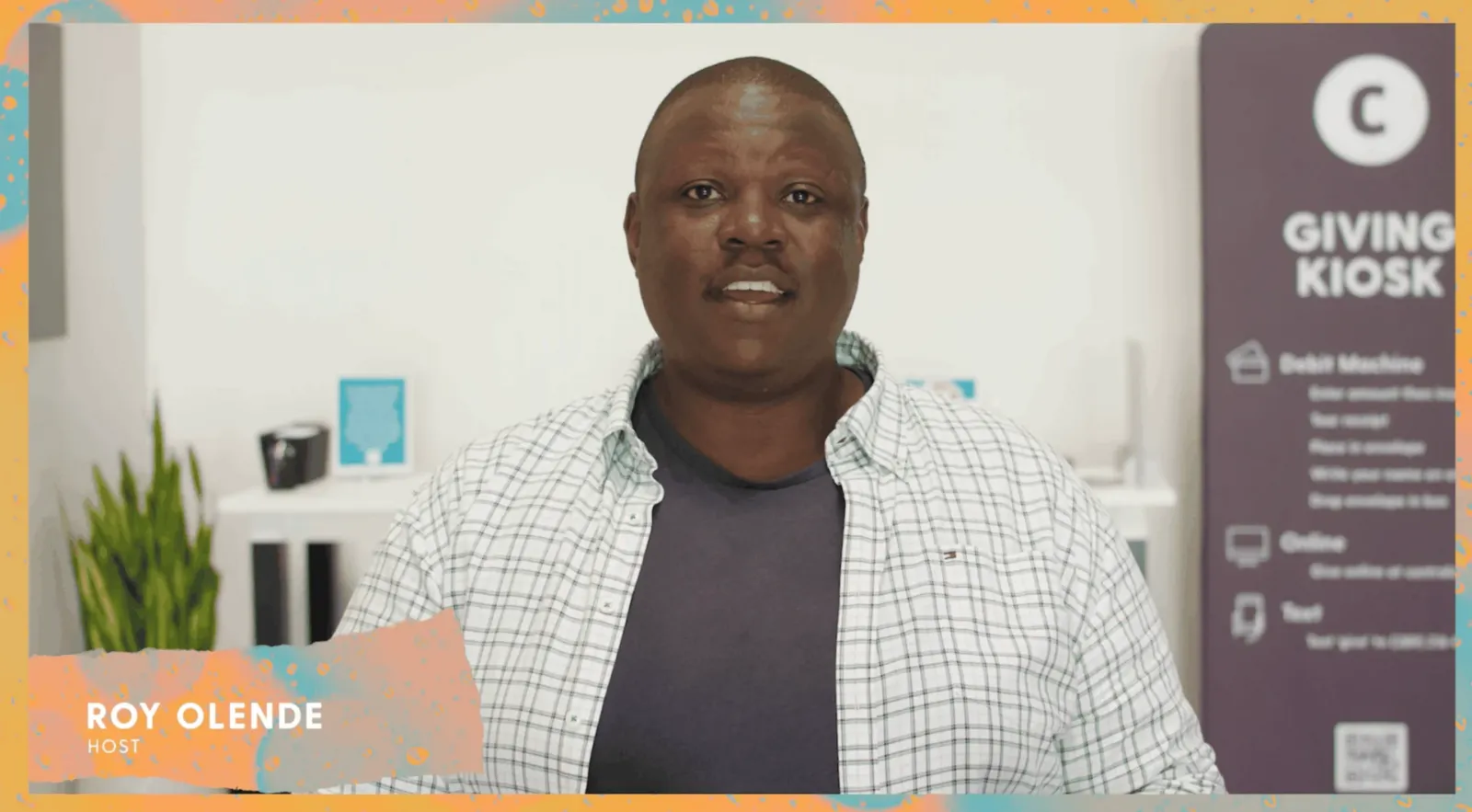 Roy Olende, host of Central's giving video, speaking in front of the Giving Kiosk in the church lobby.