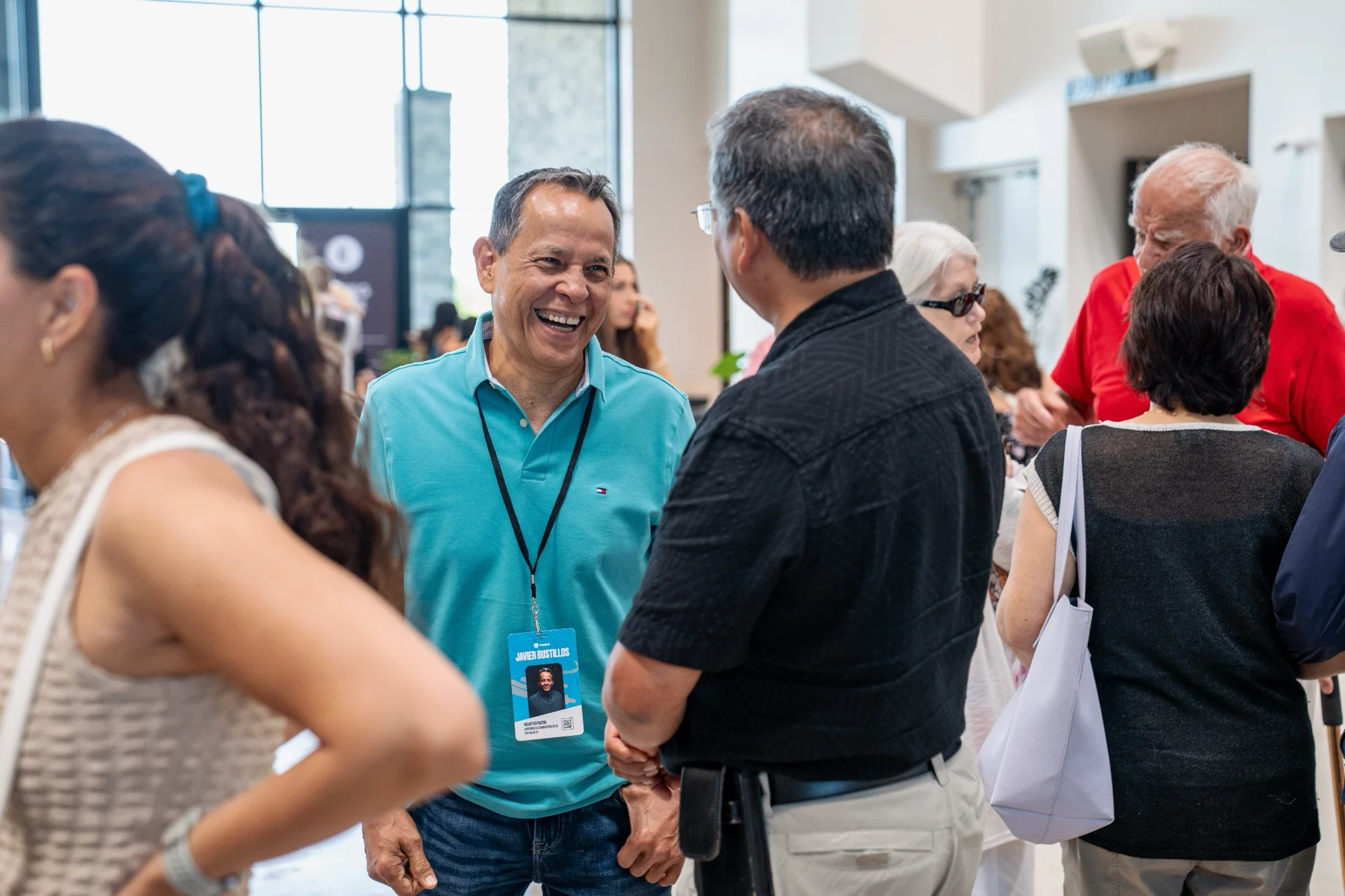 People of different ages talking and laughing together in the church lobby.