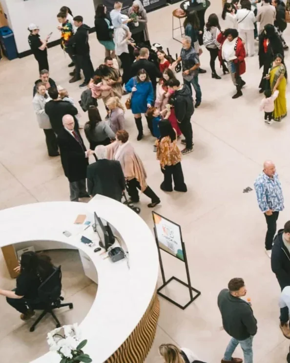 The large curved white check-in desk in the middle of the Central lobby, with a team member seated at it and families gathered nearby.